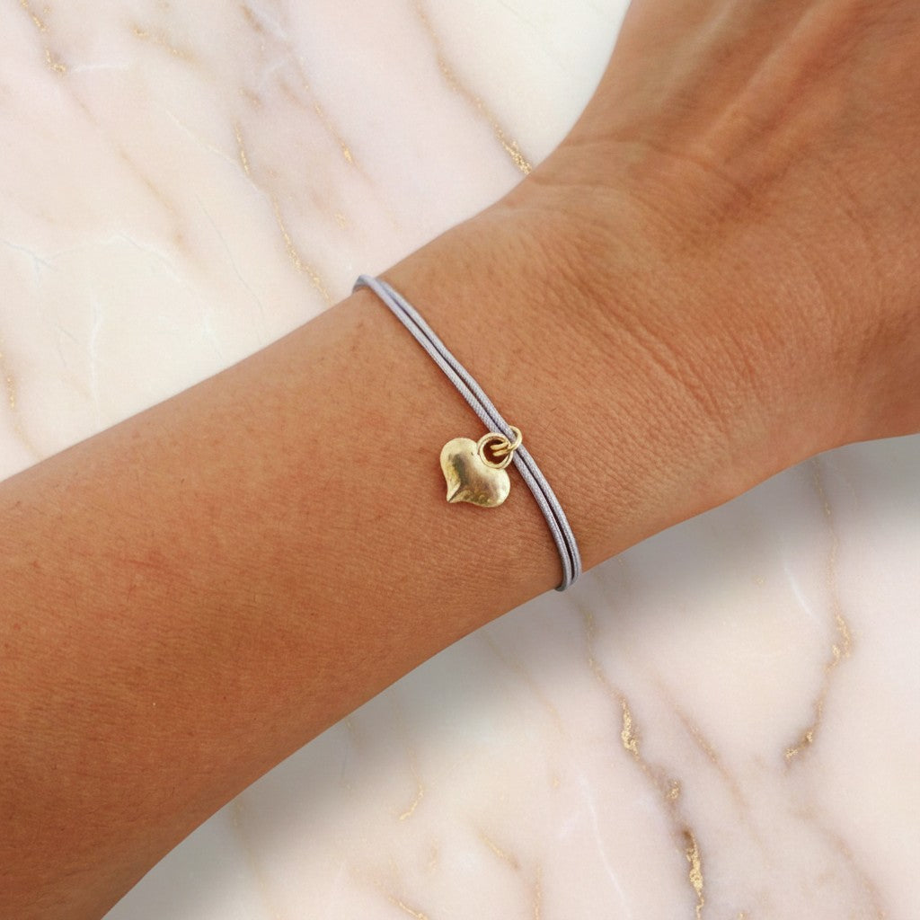 ZOA HANDMADE delicate grey cord bracelet with a small gold heart charm. Adjustable length with stainless steel elements.